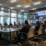 a dynamic office training session showcases engaged employees gathered around a sleek conference table, with vibrant visuals on a digital screen inspiring motivation and teamwork.